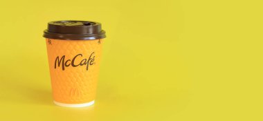 Kyiv, Ukrayna - 21 Mart 2024: Sarı arka planda McDonald 's fast food restoran logosu olan kağıt bardak latte. Yakın plan kahve. Tek kullanımlık sarı karton bardakta Latte. Boşluğu kopyala