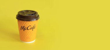 Kyiv, Ukrayna - 21 Mart 2024: Sarı arka planda McDonald 's fast food restoran logosu olan kağıt bardak latte. Yakın plan kahve. Tek kullanımlık sarı karton bardakta Latte. Boşluğu kopyala