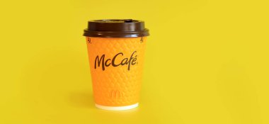 Kyiv, Ukrayna - 21 Mart 2024: Sarı arka planda McDonald 's fast food restoran logosu olan kağıt bardak latte. Yakın plan kahve. Tek kullanımlık sarı karton bardakta Latte. Boşluğu kopyala