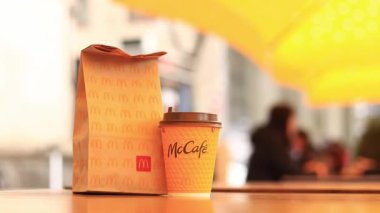 Kyiv, Ukrayna - 22 Mart 2024: İçinde McDonald 's fast food restoranından alınmış yiyecekler ve tek kullanımlık sarı karton bardakta bir latte olan bir kağıt torba. Verandada fast food. Kahveli karton bardak.