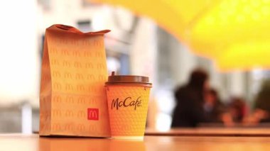 Kyiv, Ukrayna - 22 Mart 2024: İçinde McDonald 's fast food restoranından alınmış yiyecekler ve tek kullanımlık sarı karton bardakta bir latte olan bir kağıt torba. Verandada fast food. Kahveli karton bardak.