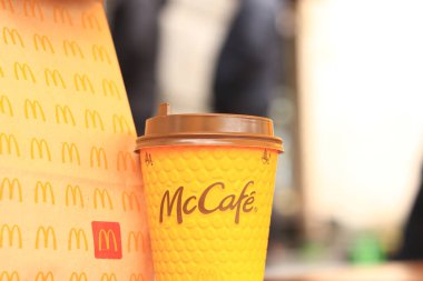 Kyiv, Ukrayna - 22 Mart 2024: İçinde McDonald 's fast food restoranından alınmış yiyecekler ve tek kullanımlık sarı karton bardakta bir latte olan bir kağıt torba. Verandada fast food. Kahveli karton bardak.