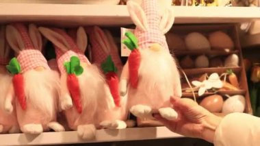 Kyiv, Ukrayna - 26 Mart 2024: Yumuşak oyuncak. Kadın elleri tavşan kulaklı pelüş bir cüce tutuyor, yakın plan. Mağazada oyuncak satmak. Pofuduk bir oyuncak seçen bir alıcının yakın çekimi