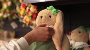 Kyiv, Ukrayna - 26 Mart 2024: Yumuşak oyuncak. Kadınların elleri pelüş bir tavşan tutar, yakın plan. Mağazada oyuncak satmak. Paskalya tavşanını seçen bir müşterinin yakın çekimi.