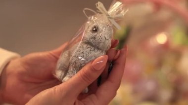 Kyiv, Ukrayna - 26 Mart 2024: Tavşan şeklinde Paskalya mumu. Kadınların elleri bir tavşan mumunu yakından tutar. Bir mağazada dekor satmak. Hediye seçen bir müşterinin yakın çekimi.