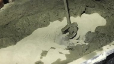 Beton sıva, havan topu. Çekiç matkabıyla çimento harcı karıştırmak, konakta inşaat. Bir inşaatçı çimento alçısını hazırlar, yakın plan. İnşaat alanında çimento harcı.