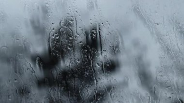 Pencere camına yağmur yağıyor, su izleri var. Arabadan yağmurun manzarası. Cama yağmur damlaları, bulanık arka plan. İyi akşamlar.