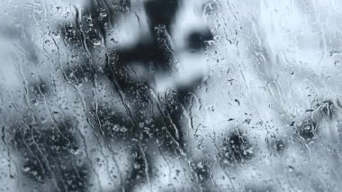 Pencere camına yağmur yağıyor, su izleri var. Arabadan yağmurun manzarası. Cama yağmur damlaları, bulanık arka plan. İyi akşamlar.
