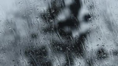 Pencere camına yağmur yağıyor, su izleri var. Arabadan yağmurun manzarası. Cama yağmur damlaları, bulanık arka plan. İyi akşamlar.
