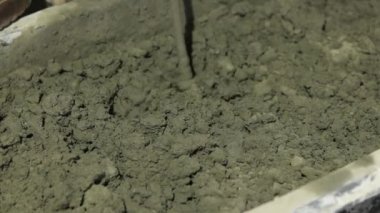 Beton sıva, havan topu. Çekiç matkabıyla çimento harcı karıştırmak, konakta inşaat. Bir inşaatçı çimento alçısını hazırlar, yakın plan. İnşaat alanında çimento harcı.