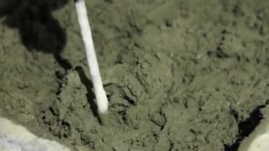 Beton sıva, havan topu. Çekiç matkabıyla çimento harcı karıştırmak, konakta inşaat. Bir inşaatçı çimento alçısını hazırlar, yakın plan. İnşaat alanında çimento harcı.