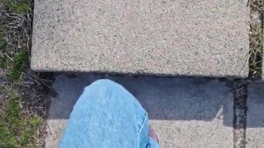 Basamakları tırmanan insan ayaklarına yakın çekim. Bahar ya da yaz aylarında parkta yürüyüş. Yürüyüş. Kot pantolonlu ve spor ayakkabılı bir kadın parkta yürüyor, levhalardan basamaklar.