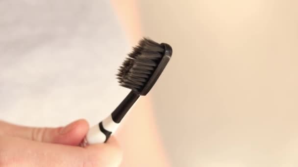 把牙膏压在牙刷上 刷你的牙医疗保健 口腔卫生 一个女人把白色的牙膏从管子里挤到了黑色的牙刷上 早上卫生程序 — 图库视频影像