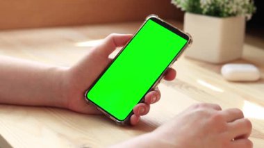 Elinde akıllı telefondan krom anahtar modeli var. Uygulama veya web sitesi tasarımı için kopya alanı gösteriliyor. Ahşap masa arkasında boş yeşil ekranlı akıllı telefonu olan bir kadın. Akıllı telefonun yakın plan görüntüsü
