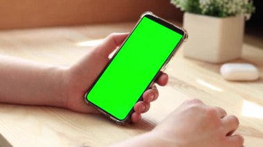 Elinde akıllı telefondan krom anahtar modeli var. Uygulama veya web sitesi tasarımı için kopya alanı gösteriliyor. Ahşap masa arkasında boş yeşil ekranlı akıllı telefonu olan bir kadın. Akıllı telefonun yakın plan görüntüsü