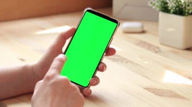 Elinde akıllı telefondan krom anahtar modeli var. Uygulama veya web sitesi tasarımı için kopya alanı gösteriliyor. Ahşap masa arkasında boş yeşil ekranlı akıllı telefonu olan bir kadın. Akıllı telefonun yakın plan görüntüsü