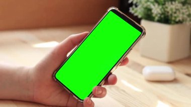 Elinde akıllı telefondan krom anahtar modeli var. Uygulama veya web sitesi tasarımı için kopya alanı gösteriliyor. Ahşap masa arkasında boş yeşil ekranlı akıllı telefonu olan bir kadın. Akıllı telefonun yakın plan görüntüsü