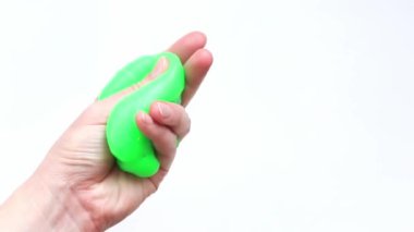 Kız yeşil balçık yoğuruyor. Kadının elleri beyaz arka planda parlak yeşil balçığı gerer. Rahatlamak için stres önleyici oyuncak. Eğlenceli bir duyusal aktivite. Oyuncakçı konsepti