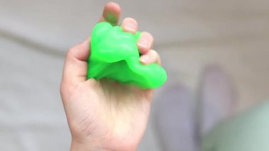 Kız yeşil balçık yoğuruyor. Parlak yeşil balçığı geren kadın eller, üst manzara. Rahatlamak için stres önleyici oyuncak. Eğlenceli bir duyusal aktivite. Oyuncakçı konsepti