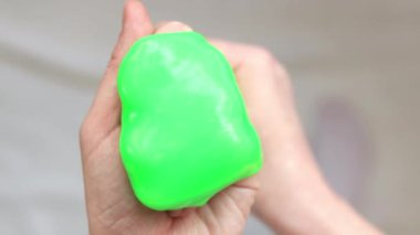 Kız yeşil balçık yoğuruyor. Parlak yeşil balçığı geren kadın eller, üst manzara. Rahatlamak için stres önleyici oyuncak. Eğlenceli bir duyusal aktivite. Oyuncakçı konsepti