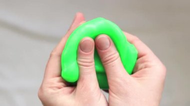 Kız yeşil balçık yoğuruyor. Parlak yeşil balçığı geren kadın eller, üst manzara. Rahatlamak için stres önleyici oyuncak. Eğlenceli bir duyusal aktivite. Oyuncakçı konsepti