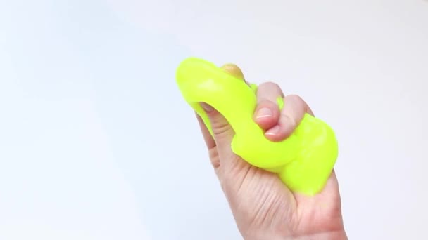 这个女孩把黄色的黏液揉碎了 雌性手伸展明亮的黄色黏液 白色背景 用于放松的抗压玩具 一个有趣的感觉活动 玩具商店的概念 — 图库视频影像