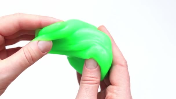 这个女孩揉搓绿色黏液 女人的手伸出明亮的绿色黏液在白色背景的特写 用于放松的抗压玩具 一个有趣的感觉活动 玩具商店的概念 — 图库视频影像