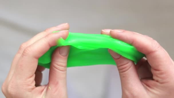 这个女孩揉搓绿色黏液 雌性手伸出明亮的绿色黏液特写 顶部视图 用于放松的抗压玩具 一个有趣的感觉活动 玩具商店的概念 — 图库视频影像