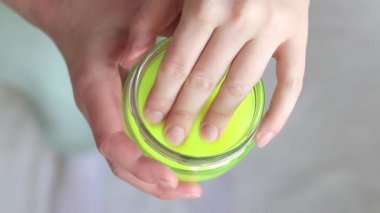 Kız sarı mukusu yoğuruyor. Kadının elleri parlak sarı balçığı yakından gerer. Rahatlamak için stres önleyici bir oyuncak. Kafanı işten ya da okuldan uzaklaştıracak bir şey. Eğlenceli bir duyusal aktivite