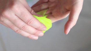 Kız sarı mukusu yoğuruyor. Kadının elleri parlak sarı balçığı yakından gerer. Rahatlamak için stres önleyici bir oyuncak. Kafanı işten ya da okuldan uzaklaştıracak bir şey. Eğlenceli bir duyusal aktivite