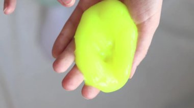 Kız sarı mukusu yoğuruyor. Kadının elleri parlak sarı balçığı yakından gerer. Rahatlamak için stres önleyici bir oyuncak. Kafanı işten ya da okuldan uzaklaştıracak bir şey. Eğlenceli bir duyusal aktivite