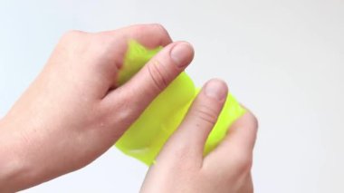 Kız sarı mukusu yoğuruyor. Kadın elleri parlak sarı sümüksü balçığı yakın plan, beyaz arka plan. Rahatlamak için stres önleyici oyuncak. Eğlenceli bir duyusal aktivite. Oyuncakçı konsepti