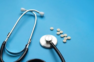 Steteskop, haplar ve mavi arka planda şırınga, seçici odaklanma. Kardiyoloji ve sağlık konsepti. Auscultation cihazı. Tıbbi bakım konsepti. Tıbbi alet. Auscultation aparatı