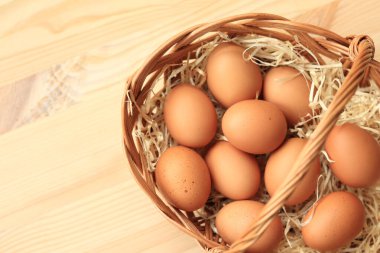 Hasır sepette tavuk yumurtası, üst manzara. Ahşap arka planda yumurtalar. Taze çiğ yumurta. Tahta bir masada sepetteki kahverengi tavuk yumurtaları. Metin için boşluk
