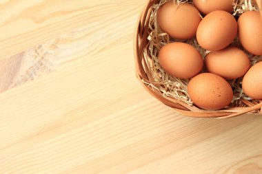 Hasır sepette tavuk yumurtası, üst manzara. Ahşap arka planda yumurtalar. Taze çiğ yumurta. Tahta bir masada sepetteki kahverengi tavuk yumurtaları. Metin için boşluk