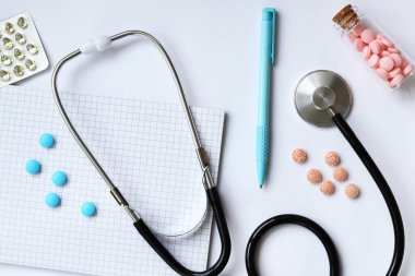 Steteskop, not defteri ve arka planda kalem, üst manzara. Kardiyoloji ve sağlık konsepti. Auscultation aparatı. Tıbbi bakım konsepti. Steteskop ve ilaçlar. Terapistin masası.