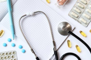 Steteskop, not defteri ve arka planda kalem, üst manzara. Kardiyoloji ve sağlık konsepti. Auscultation aparatı. Tıbbi bakım konsepti. Steteskop ve ilaçlar. Terapistin masası.