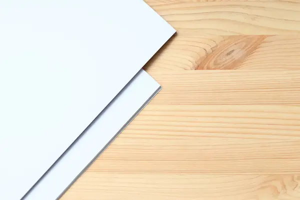 White blank paper on a wooden table, top view. A small stack of A4 sheets on the desktop, close-up. Blank paper, space for text, mockup