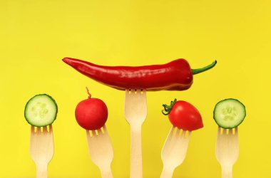 Biber, domates, salatalık ve turp tek kullanımlık ahşap çatallar, yakın plan, sarı arka plan. Sağlıklı beslenme konsepti. Diyetteki taze sebzeler. Parlak bir arka planda sebzeler. Metin için boşluk