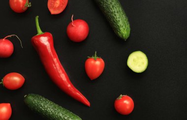Koyu arkaplanda kırmızı biber, küçük domates ve salatalık. Yiyecek ve taze sebze konsepti. Büyük biber, yeşil salatalık ve kiraz domatesleri. Metin için yer