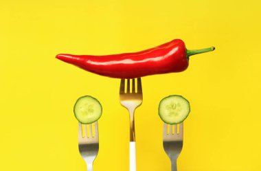 Çatallı kırmızı biber ve salatalık, sarı arka plan. Sarı arka planda salata için acı kırmızı biber ve sebze. Yiyecek ve taze sebze konsepti