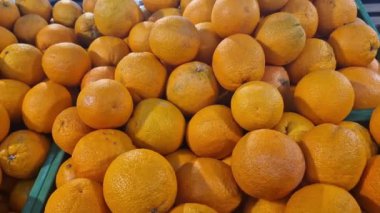 Süpermarkette portakal satışı. Plastik kutularda citrus meyveleri, seçici odaklı yakın çekim. Portakallar mağazanın yan görünümünde. Olgun, sulu, parlak portakal meyvesi. C vitamini ile zenginleştirilmiş meyve.