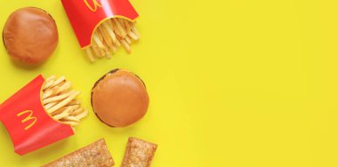 Kyiv, Ukrayna - 31 Ocak 2024: Kağıt ambalajda patates kızartması, sarı arka planda vişneli turta ve çizburger. McDonald 's Corporation dünyanın en büyük fast food restoranıdır. Boşluğu kopyala