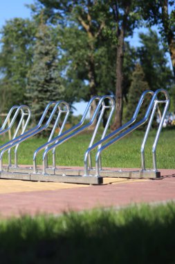 Parkta bisikletler için park etmek. Bisikletleri yakın çekimde park etmek için metal yapı. Yaz havasında bisiklet parkı, seçici bir odak noktası. Fotoğraf yer seviyesinden