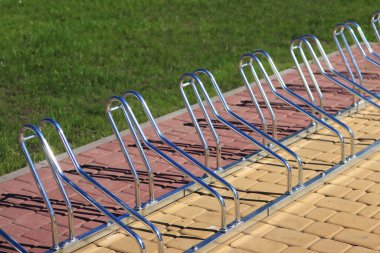 Parkta bisikletler için park etmek. Bisikletleri yakın çekimde park etmek için metal yapı. Yaz havasında bisiklet parkı, seçici bir odak noktası. Fotoğraf yer seviyesinden