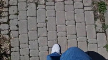 Spor ayakkabılı kadın bacakları, birinci şahıs görüşü. Yürüyüş, yürüyüş. Kotlu insan bacakları ve sokakta yürüyen beyaz spor ayakkabılar. Bahar ya da yaz aylarında, güzel havada yürü. Beyaz ayakkabılar