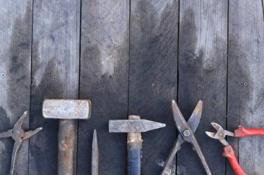 Tahta bir yüzey üzerinde eski iş aletleri, üst manzara. Çekiç, balyoz, metal makas, kerpeten ve daha fazlası. El aleti. İnşaat Günü ya da Babalar Günü. İnşaat ve yenileme konsepti