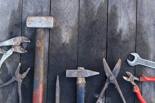 Tahta bir yüzey üzerinde eski iş aletleri, üst manzara. Çekiç, balyoz, metal makas, kerpeten ve daha fazlası. El aleti. İnşaat Günü ya da Babalar Günü. İnşaat ve yenileme konsepti