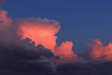 Gün batımı bulutları. Bulutlar koyu gökyüzüne karşı pembeye boyanmış. Doğal arkaplan