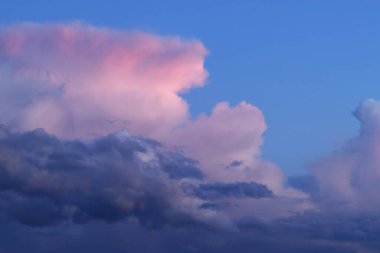 Gün batımı bulutları. Bulutlar koyu gökyüzüne karşı pembeye boyanmış. Doğal arkaplan